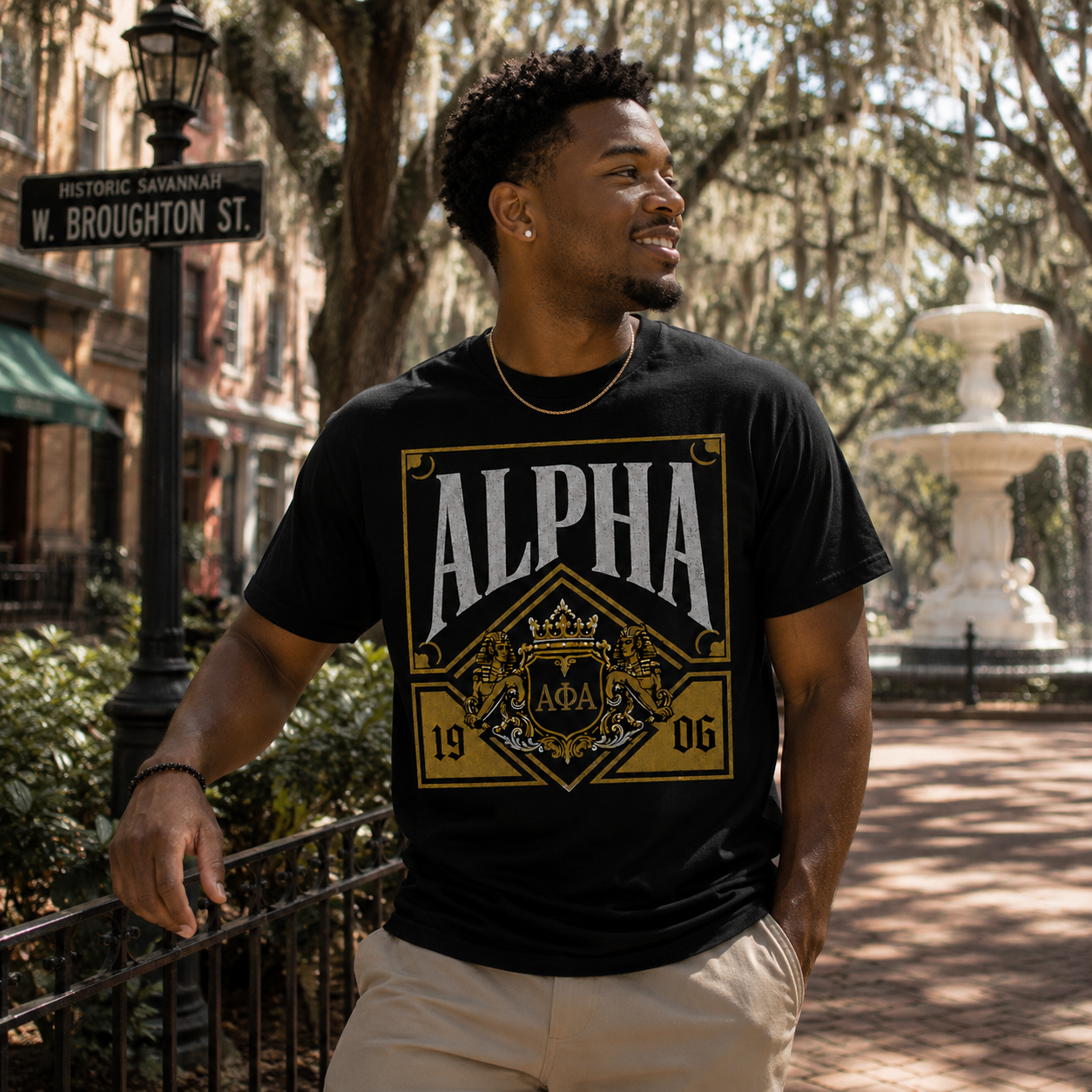 Model wearing the Alpha Phi Alpha Heritage Crest black T-shirt with gold and gray fraternity graphic