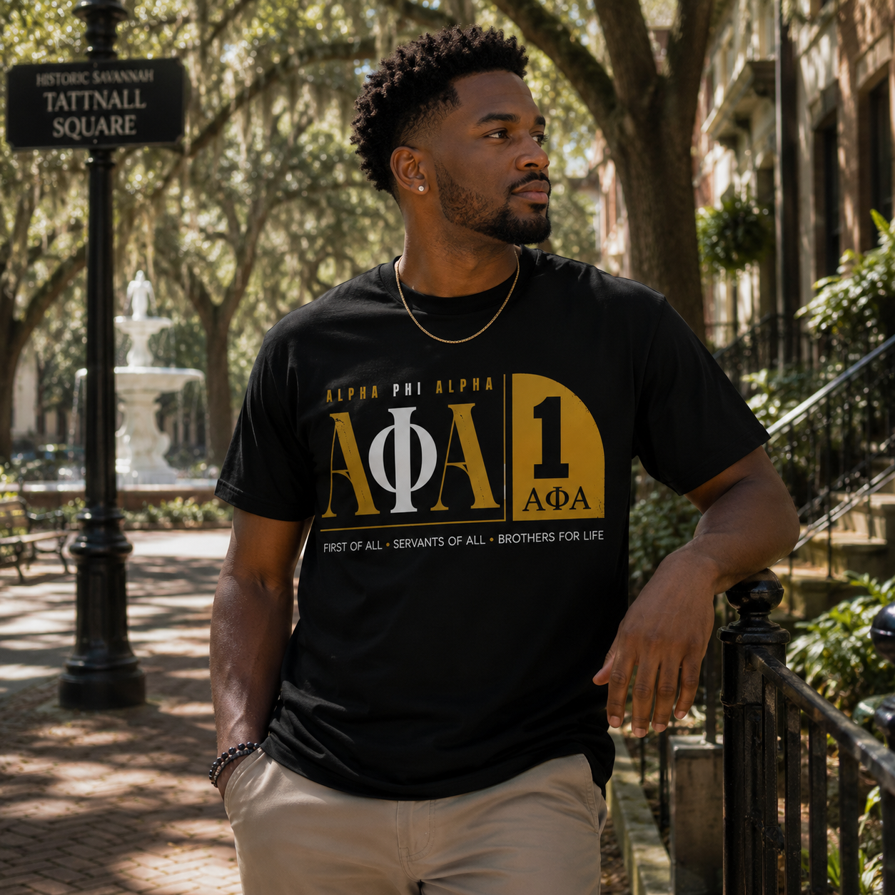 Model wearing the Alpha Phi Alpha No. 1 1906 black T-shirt with gold and white ΑΦΑ graphic