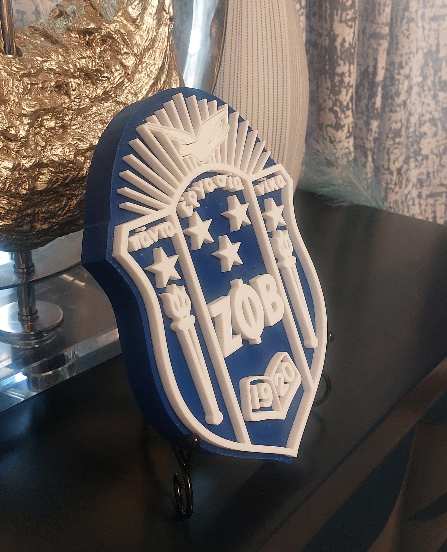 A 3D shield-shaped decoration featuring blue and white colors with star motifs, mounted on a wall.