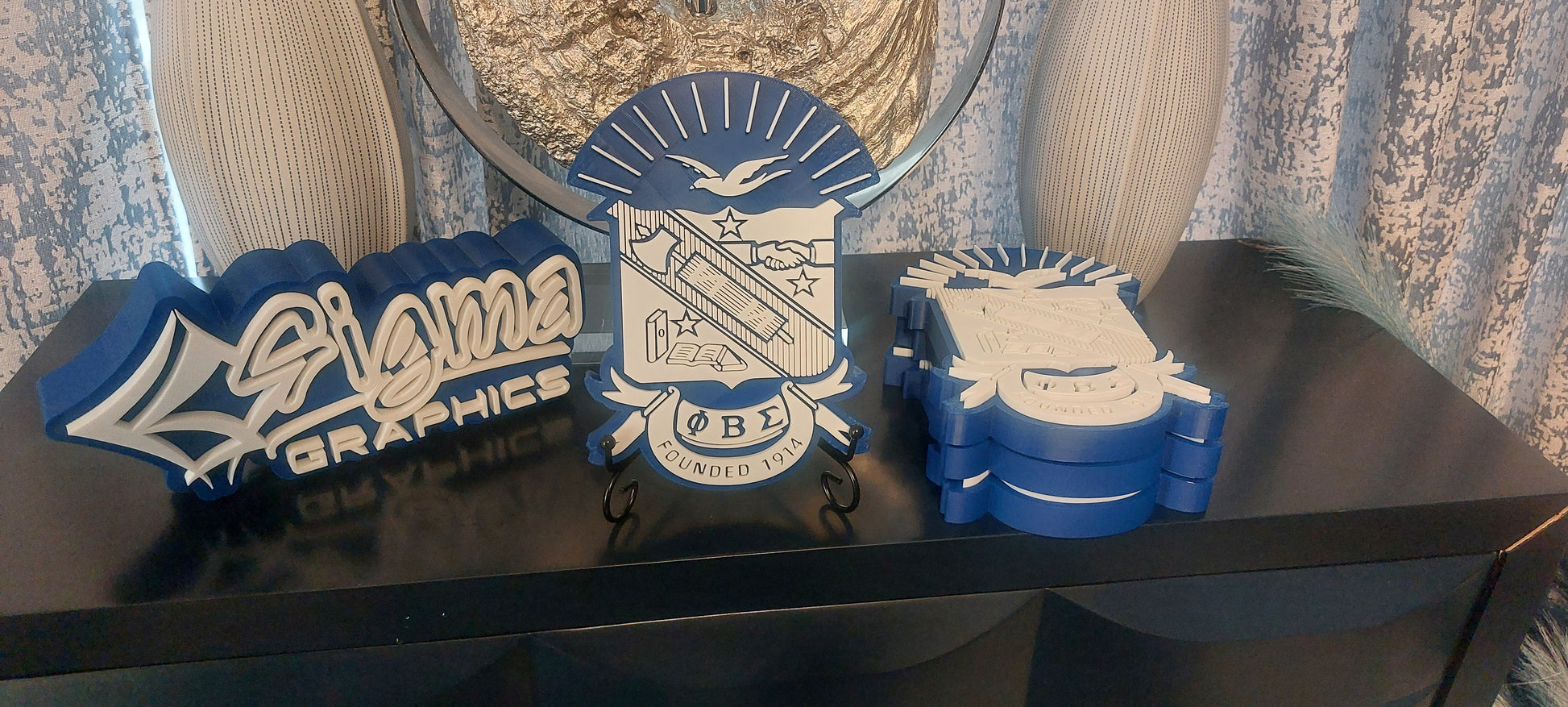 A blue and gold 3D shield with Phi Beta Sigma graphics displayed on a table.