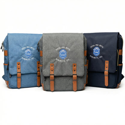 Three bags in blue, gray, and navy with brown straps on a white background
