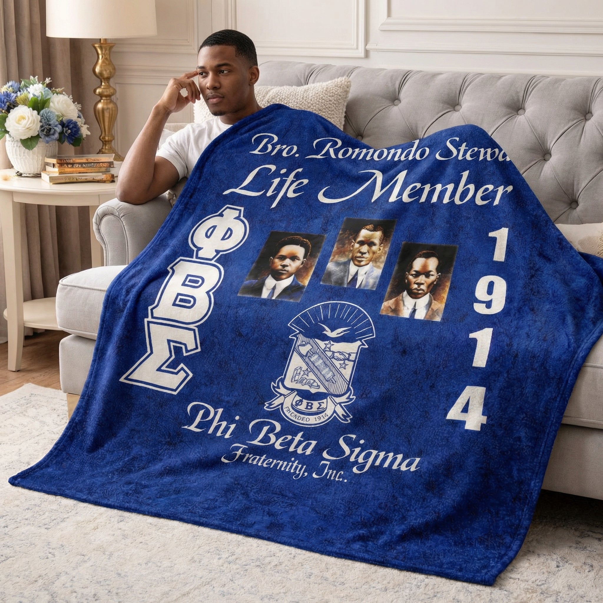Man holding a Phi Beta Sigma fraternity blanket in a living room.