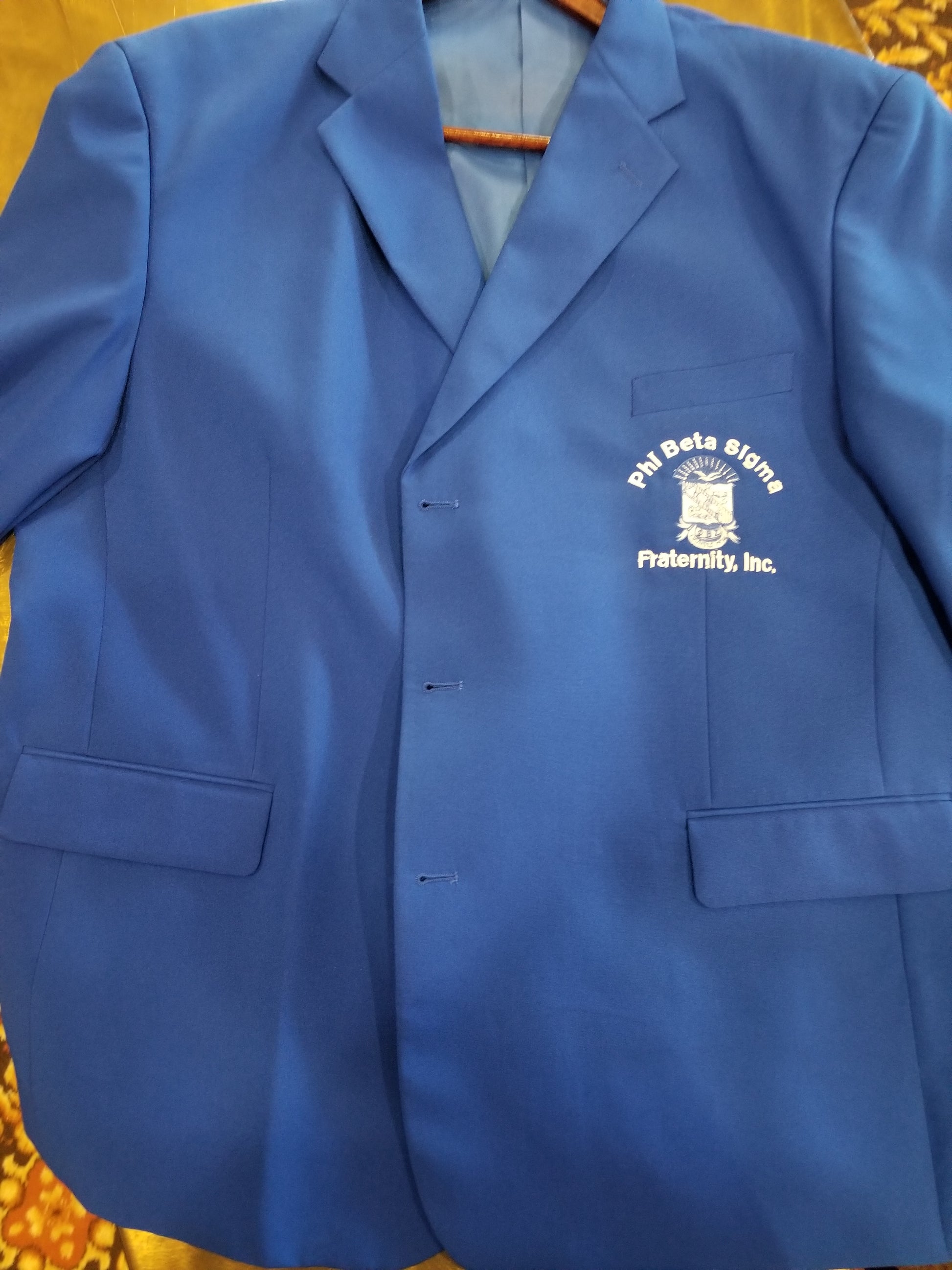 A blue Phi Beta Sigma blazer with embroidered text and logo on the front.