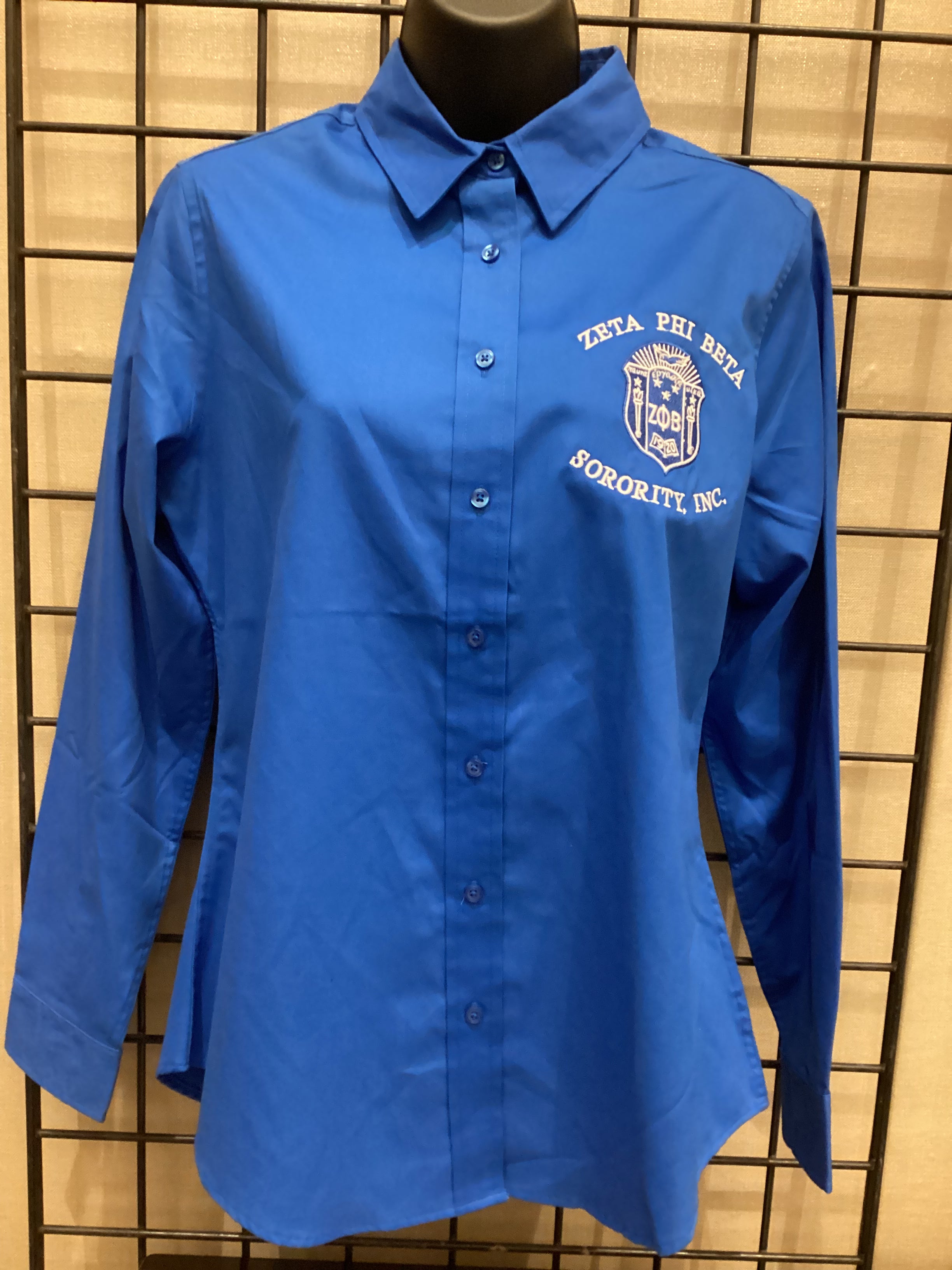 A long-sleeved blue shirt with a collar, displayed on a mannequin. The shirt features a logo on the chest.